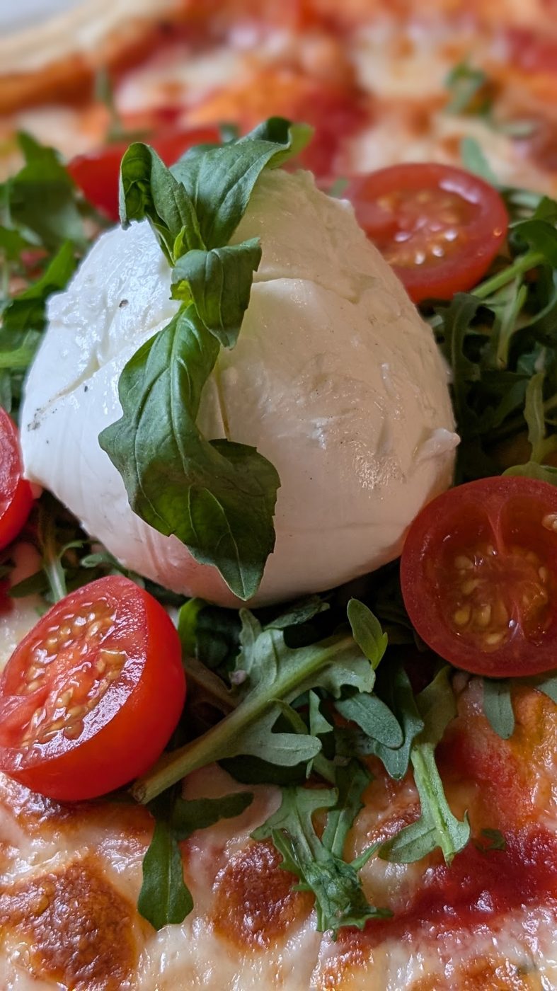 Burrata on a pizza with cherry tomatoes and basil