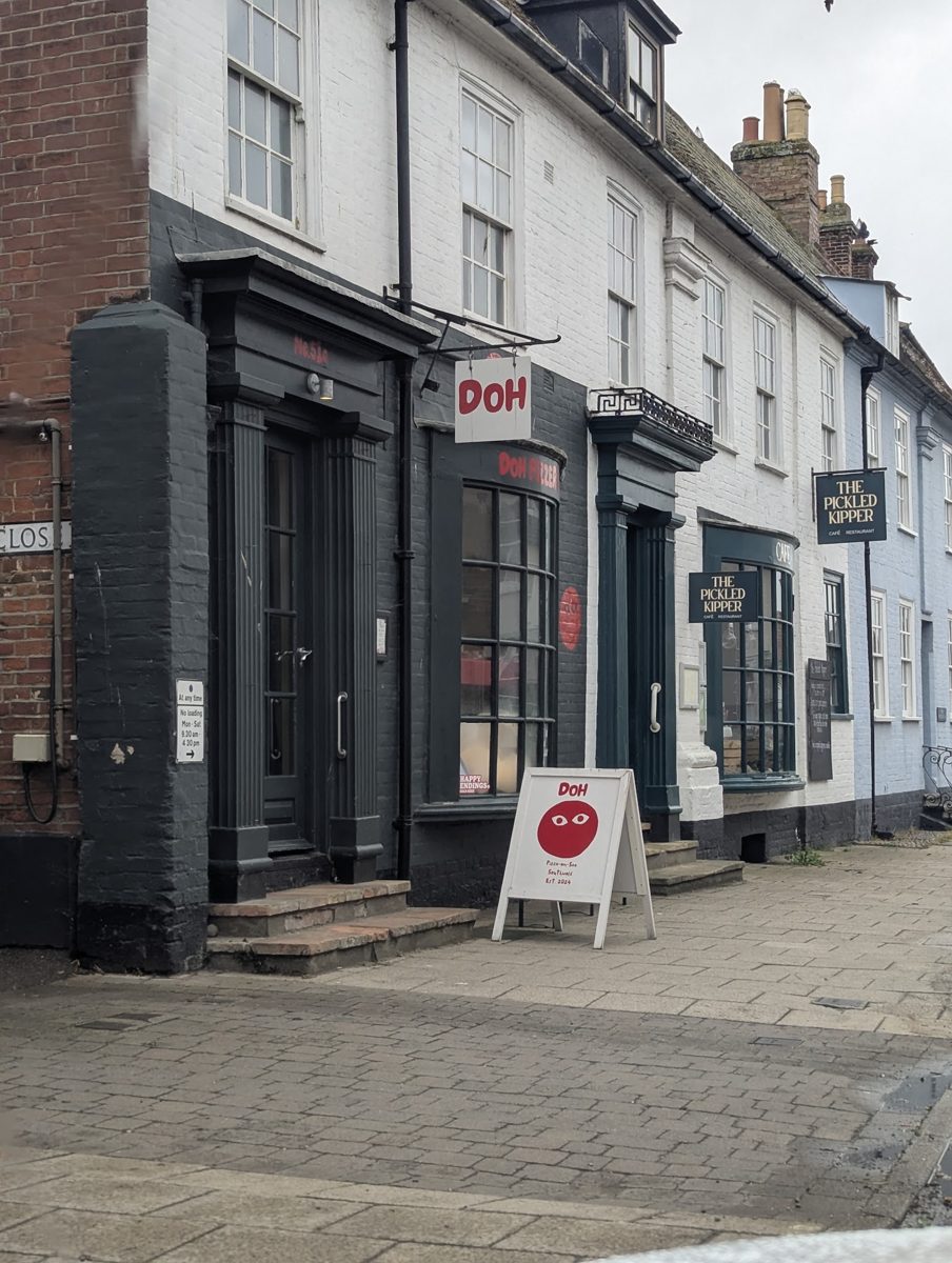 The dark-painted shopfront with the red Doh sign and an A-board